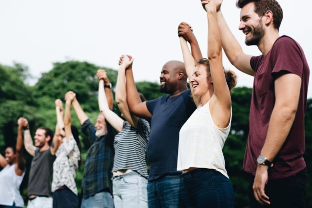 Обьединение людей- A group of smiling people holding hands together, Kenwood Management Company investor family concept